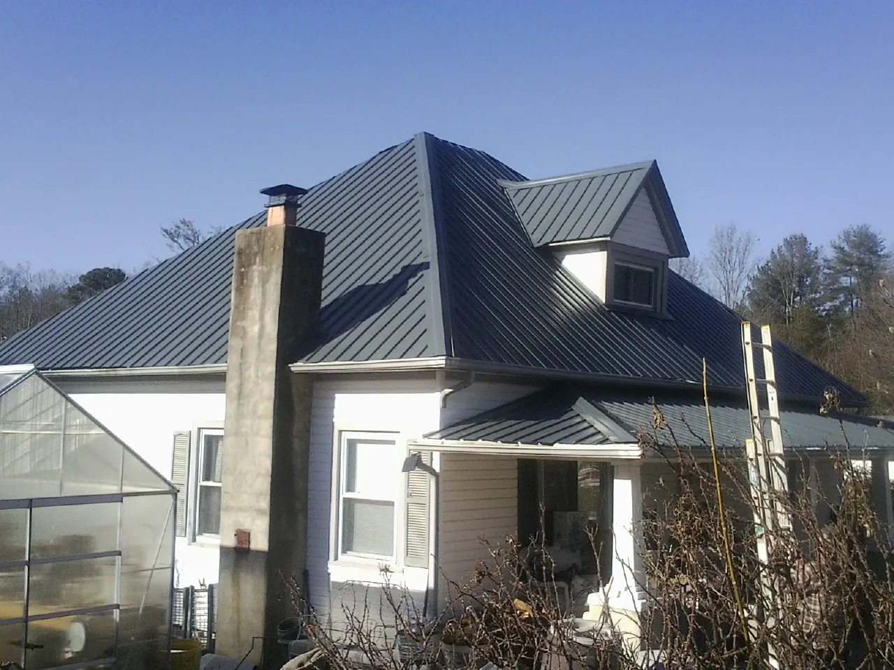 Dark blue standing seam metal roof on a white farmhouse with dormer — Slate & Tile Roof Repair by Roofing Brothers in Morganfield