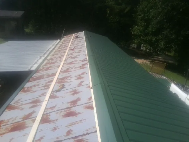 Old rusted panels beside newly installed green metal roofing — Wind Damage Roof Repair by Roofing Brothers in Morganfield