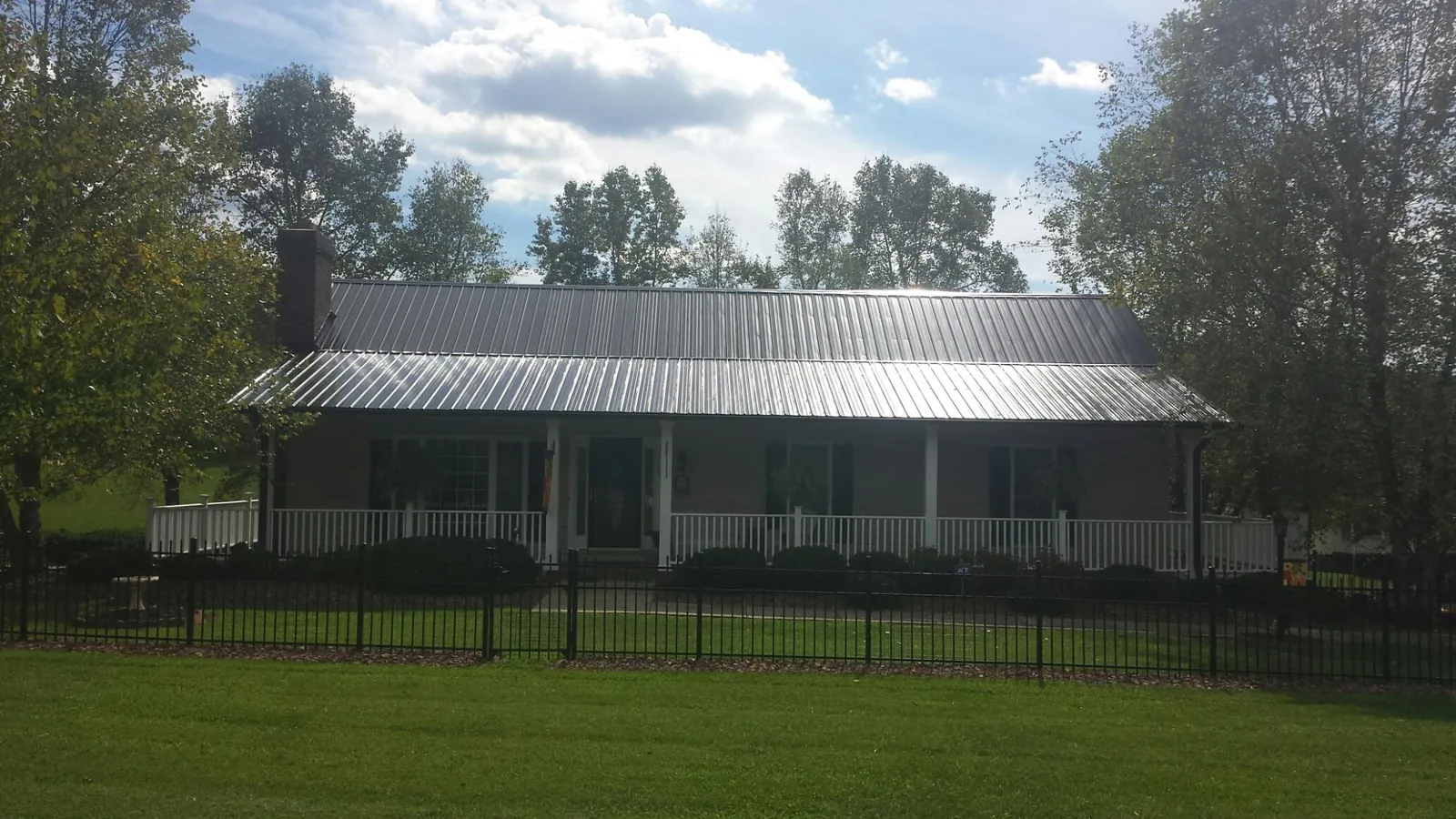 Gray metal roof on a brick ranch with a full width front porch — Gutter Guard Installation work by our crew in Morganfield