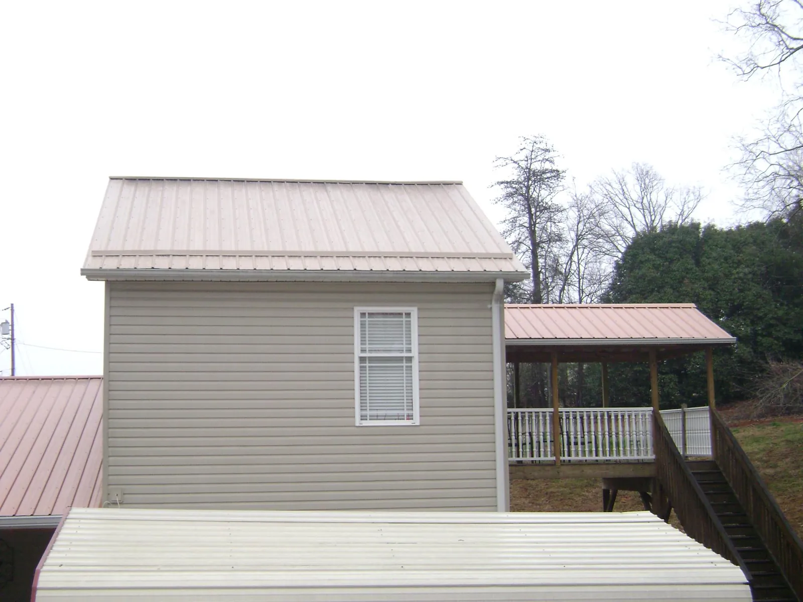 Tan metal roofs on a two story addition and attached porch, from a Roof Replacement job in Morganfield