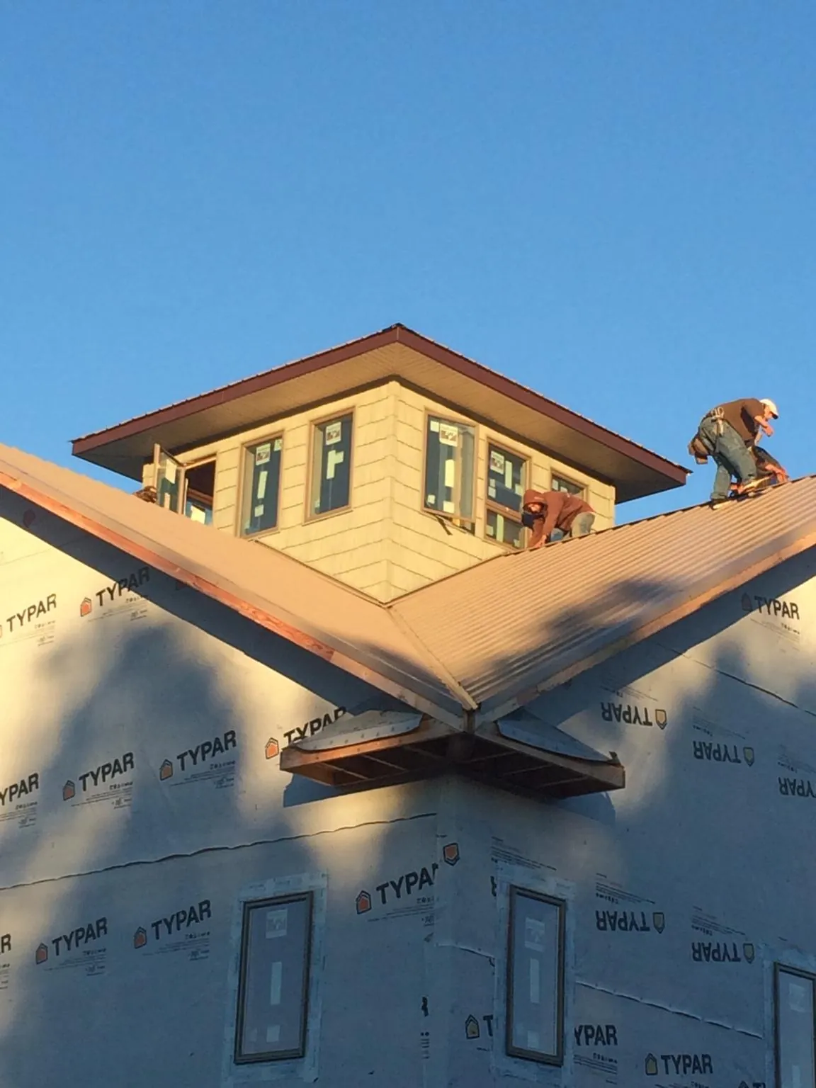 Roofers working around a rooftop cupola on a new metal roof at sunset — Roof Waterproofing in Morganfield by Roofing Brothers